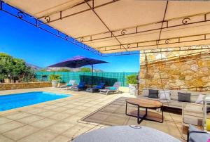 a patio with a pool and chairs and an umbrella at Villa terranga in Calenzana