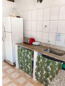 a kitchen with a sink and a white refrigerator at Suítes Vilas do atlântico a 100M da praia in Lauro de Freitas