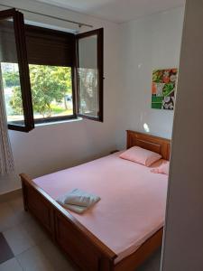 a bedroom with a bed with pink sheets and two windows at Apartmani Milena in Herceg-Novi