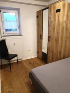 Cette chambre dispose d'une chaise et d'une porte en bois. dans l'établissement Traumhaftes Apartment mit Exclusiver Ausstattung + WLAN gratis, à Schöfweg