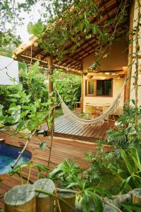 um alpendre de madeira com uma rede de descanso numa casa em Vila Nativa Caraíva em Caraíva