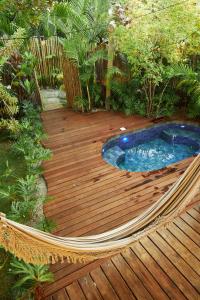 une terrasse en bois avec un bain à remous dans un jardin dans l'établissement Vila Nativa Caraíva, à Caraíva