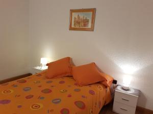 a bedroom with a bed with orange pillows on it at Apartamentos Grifovacances Nevada in Pas de la Casa