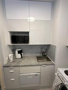 a kitchen with white cabinets and a sink and a microwave at Chic and Relaxing Studio in Hyvinkää