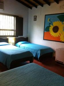 a bedroom with two beds and a painting of a sunflower at Alojamiento rural finca estrella del Quindío in Montenegro