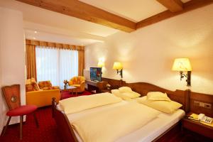 バート・ヴェーリスホーフェンにあるKurhotel Eichingerのベッドとリビングルームが備わるホテルルームです。