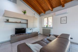 a living room with a couch and a flat screen tv at In Piazzetta holiday apartments, Barolo in Barolo