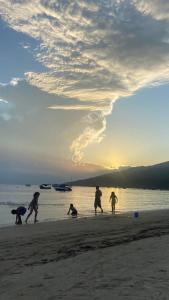 - un groupe de personnes jouant sur la plage au coucher du soleil dans l'établissement Casa em Zimbros - DISPONÍVEL CARNAVAL, à Bombinhas