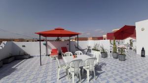 d'une terrasse avec des tables et des chaises blanches ainsi qu'un parasol. dans l'établissement Perle d'Azur F3, à Saïdia