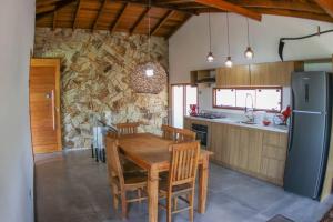 cocina con mesa de madera y pared de piedra en Casa do Zabumba, en Ilhabela