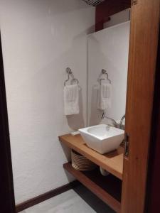 Baño blanco con lavabo y espejo en Casa do Zabumba, en Ilhabela