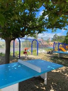 un banco azul en un parque con parque infantil en Camping Paradis Family les Rives de l'Hérault, en Gignac