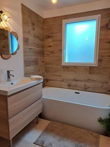 een badkamer met een wit bad en een raam bij Chambre indépendante en forêt in Plessé