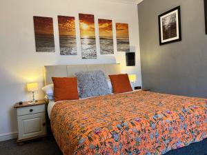 een slaapkamer met een bed en een aantal schilderijen aan de muur bij Babbacombe Palms in Torquay