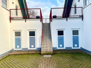 schody pomiędzy dwoma białymi budynkami z oknami w obiekcie Ferienhäuser Liethmann Haus 4 W1 w mieście Timmendorfer Strand