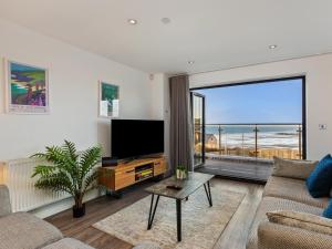 Una sala de estar con televisión y una gran ventana. en One Sand Banks, en Haverfordwest