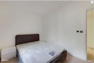 a bed in a room with a white wall at ExCeL London-Exclusive 3 Bedroom in North Woolwich
