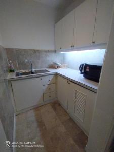 a small kitchen with white cabinets and a sink at THE ROSEMARY SUITE At TIMES SQUARE in Kuala Lumpur