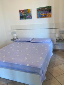 een bed in een kamer met twee schilderijen aan de muur bij Porto Cesareo - Appartamento località Torre Lapillo - Orione C10 in Torre Lapillo