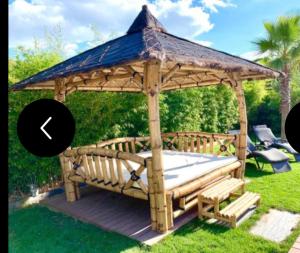 a wooden gazebo with a mattress in the grass at La bulle des coucous in Saint-Hilaire-de-Riez