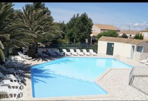 a large swimming pool with white chairs and trees at Maisonnette les Marines d'Helios T2 cabine in Marseillan