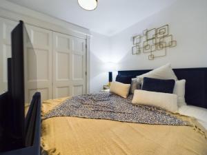 Schlafzimmer mit einem Bett mit blauen und weißen Kissen in der Unterkunft SunningEnd W King SBed EV Parking in Cheltenham