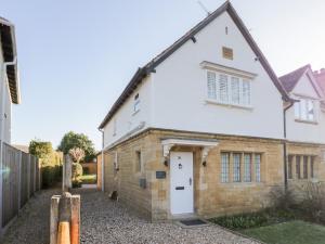 a white brick house with a white door at Dazie Cottage in Broadway