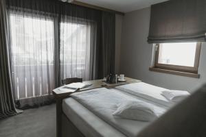 a bedroom with a bed with a table and a window at Eco & Wellness Boutique Hotel Sonne in Livigno