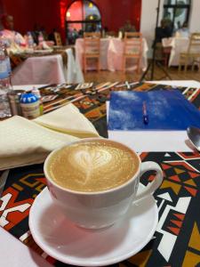 eine Tasse Kaffee auf einem Teller auf einem Tisch in der Unterkunft La Natura Guest House in Ruhengeri