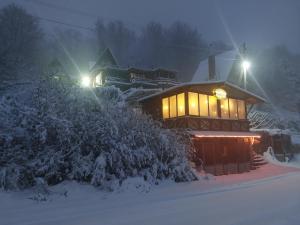 a cabin with lights on in the snow at night at Vila Jana Mavrovo in Mavrovo