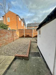 a driveway with a white fence and a brick building at Bedford town house in Bedford