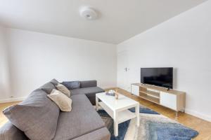 a living room with a couch and a tv at Réconfort - 15 min de Paris in Saint-Denis