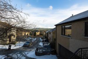 a snow covered street with cars parked next to a house at UNDERWOOD COTTAGE - Peaceful House in Kendal with views of Cumbria in Kendal