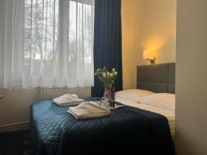 a bedroom with two beds and a vase of flowers on a table at Hotel Vistula in Krak&oacute;w
