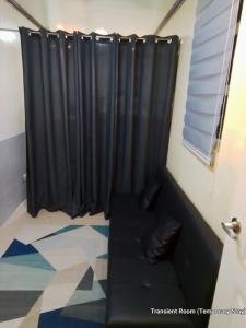 - un canapé noir dans une chambre avec fenêtre dans l'établissement Parayno's Residence, à Manille