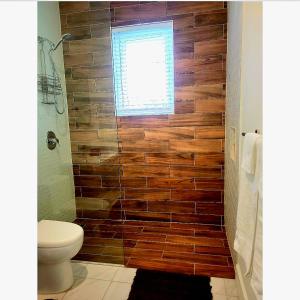 a bathroom with a toilet and a wooden wall at Loft in Paradise in Nassau