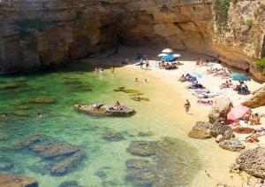 a group of people on a beach in the water at L'isola di Gianni by Ortigia Apartments in Plemmirio