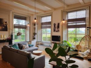 een woonkamer met een bank en een aantal ramen bij De Bloesemstee - Rustic Manor Farmhouse The Netherlands in Ruinerwold