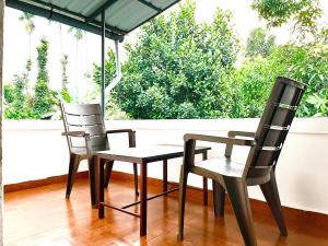 卡爾佩特塔的住宿－Sahyadri Homestay wayanad，门廊上的两把椅子和一张桌子