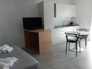 Habitación con cocina con mesa y TV. en Porta San Paolo House, en Castelbuono