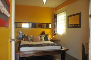 um quarto com uma cama e uma parede amarela em Mango Island Lodges em Saint Joseph