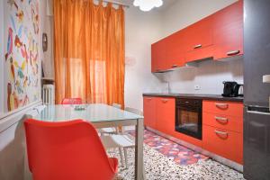 uma cozinha com uma mesa de vidro e armários laranja em La Voliera em Verona