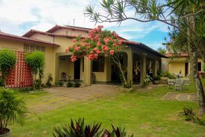 una casa con un patio con flores rosas en Casa aconchegante c jardim em Ponta Negra Natal RN, en Natal