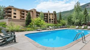 a swimming pool with chairs and a building at Chalet Fescue in Vail