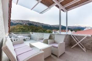 a patio with chairs and tables and a view of mountains at Apartment Ruzmarinka with Spacy Terrace in Baška