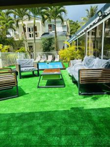 a lawn with benches and a pool in front of a house at Appartement d'une chambre avec piscine partagee terrasse amenagee et wifi a Sainte Rose in Sainte-Rose