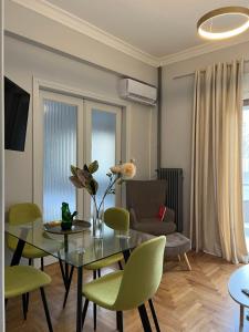 a living room with a glass table and green chairs at Acropolis Luxury Apartments Parthenon view in Athens