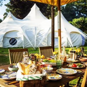 a table with food on it with tents in the background at The Mahal a Majestic 4-Bedroom Glamping Palace! in Ross on Wye