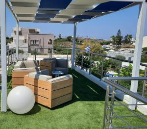 eine Terrasse mit einem Sofa und einem Stuhl auf dem Balkon in der Unterkunft Poseidon Suites Hotel in Stavros