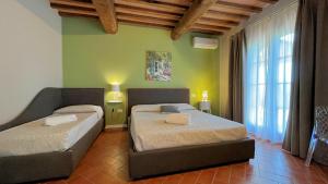2 łóżka w pokoju z zielonymi ścianami w obiekcie Borgo del Silenzio - Apartments with pool in Lajatico w mieście Laiatico +37 zdjęć